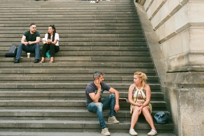 Draußen auf der Treppe sitzen zwei Paare und unterhalten sich