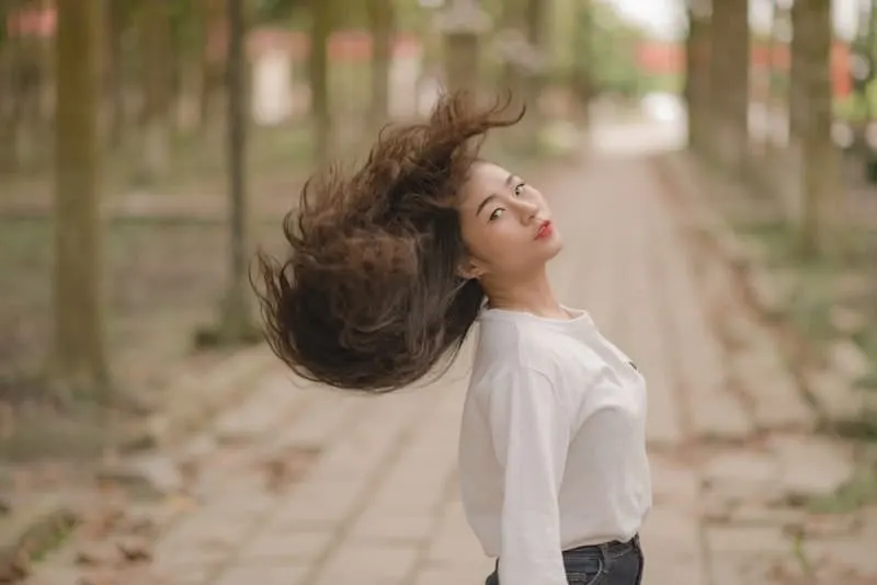 Draußen steht eine Chinesin in einem weißen Hemd mit schönen langen Haaren