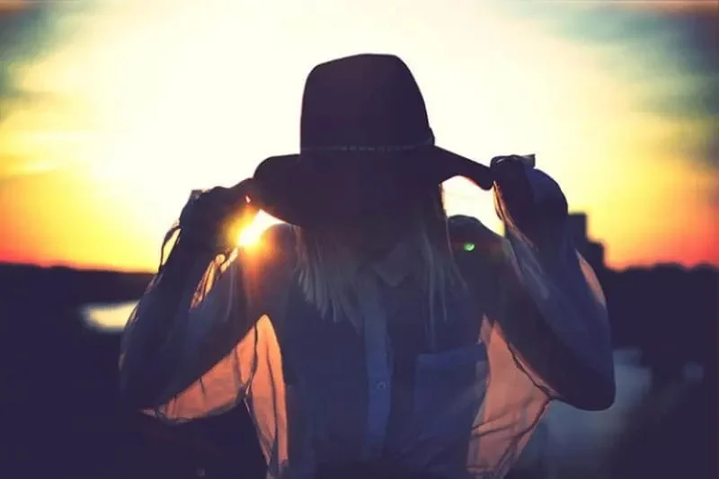 Frau mit Hut bei Sonnenuntergang