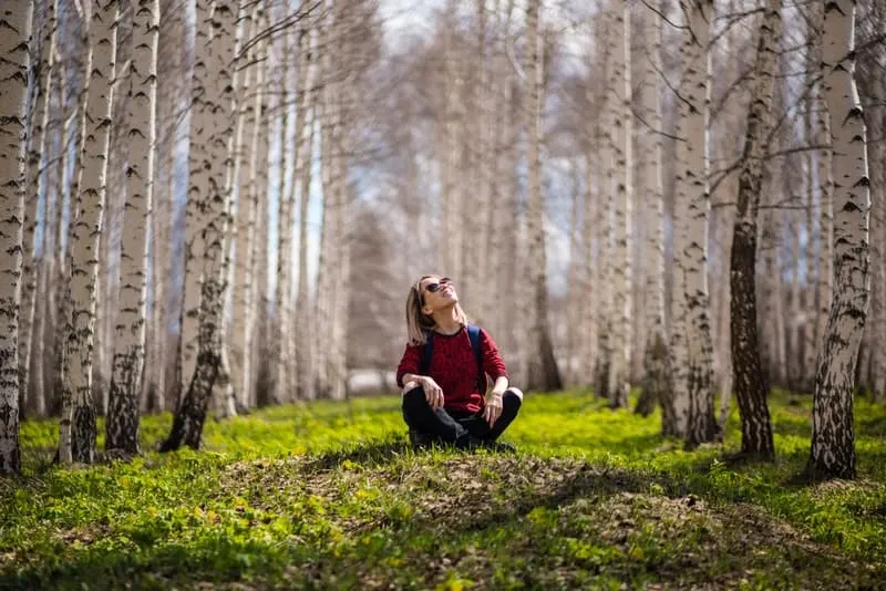 Ein Mädchen sitzt im Gras in einem Wald