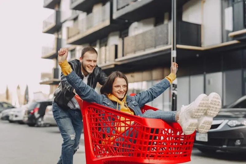 Ein Mann fährt ein Mädchen in einem Einkaufswagen
