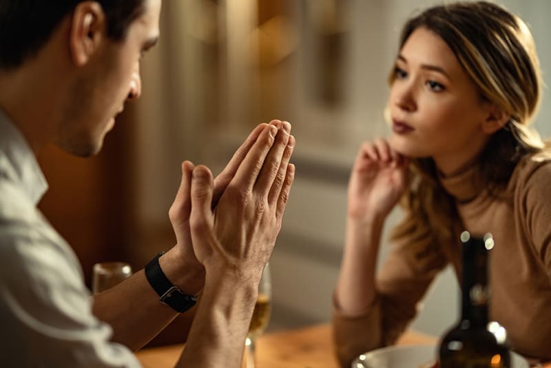 Ein Mann mit gefalteten Händen bat seine Freundin im Restaurant um Vergebung