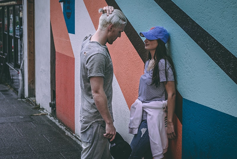 Ein Mann steht vor einer Frau, die sich an die Wand lehnt und mit ihr flirtet