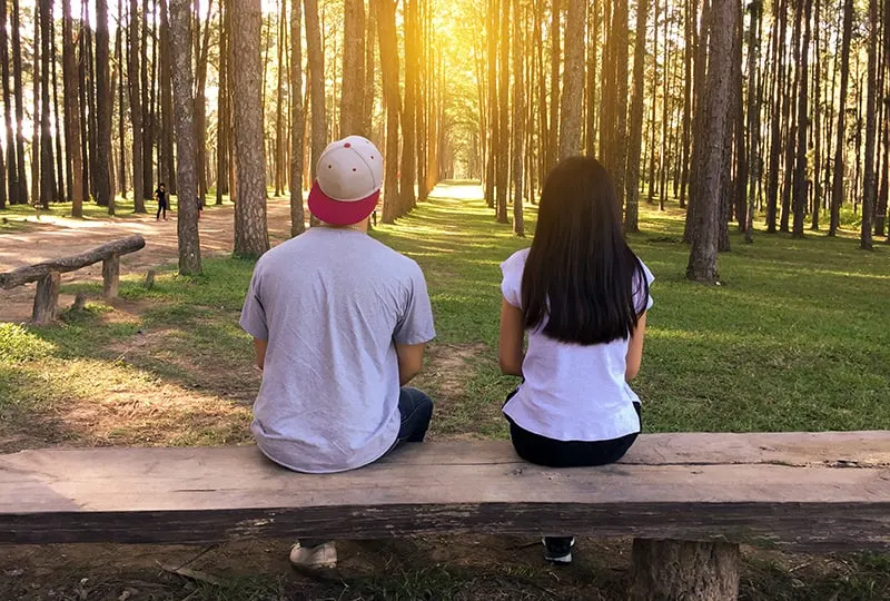 Ein Mann und eine Frau sitzen auf der Bank mit Platz zwischen ihnen im Park