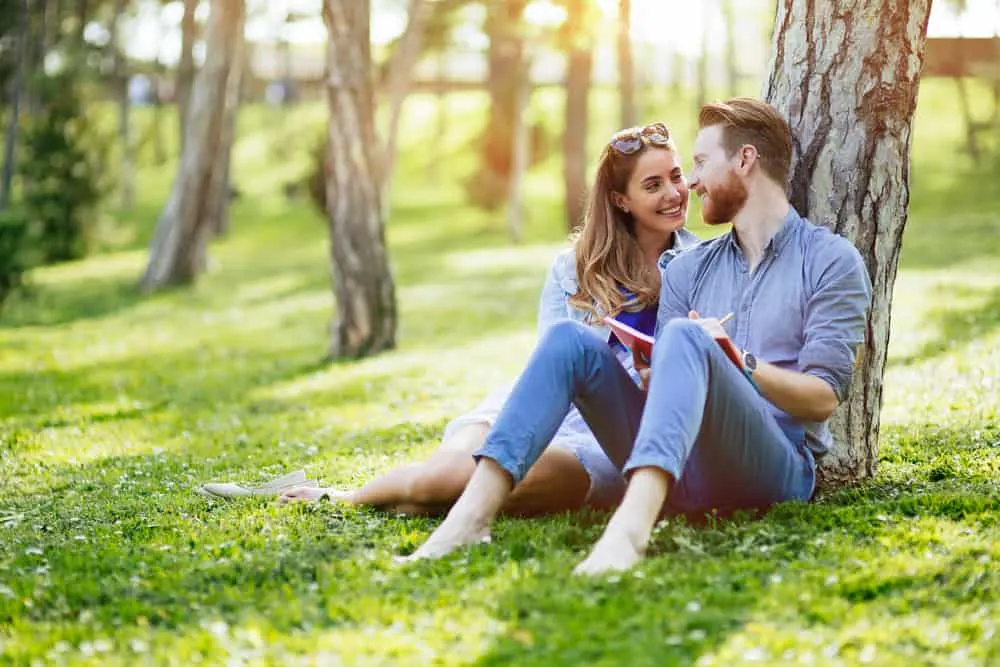 Ein Mann und eine Frau sitzen im Gras in einer Umarmung im Park