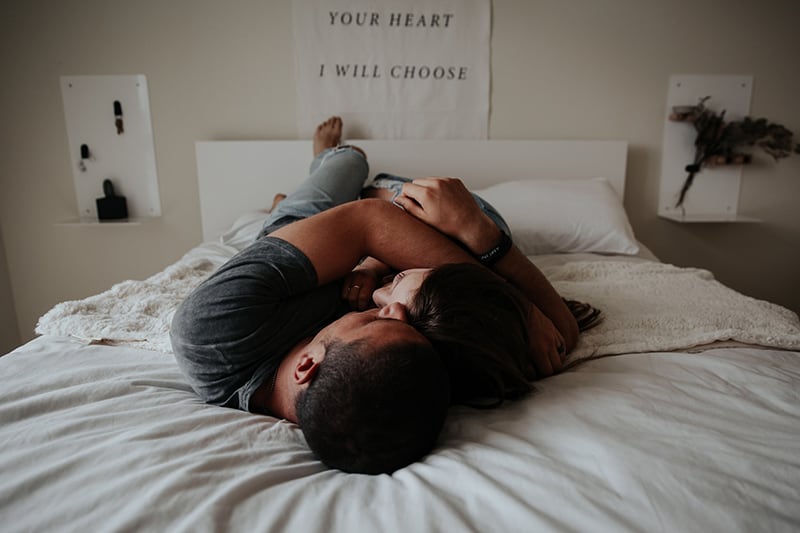 Ein Mann und eine Frau umarmen sich, während sie auf dem Bett liegen