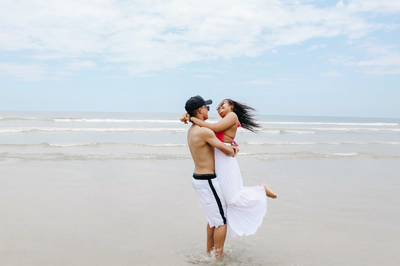 Ein glückliches Paar, das sich tagsüber am Strand umarmt