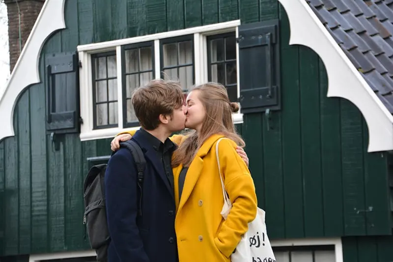 Ein junges Paar küsst sich, während es tagsüber vor dem Haus steht