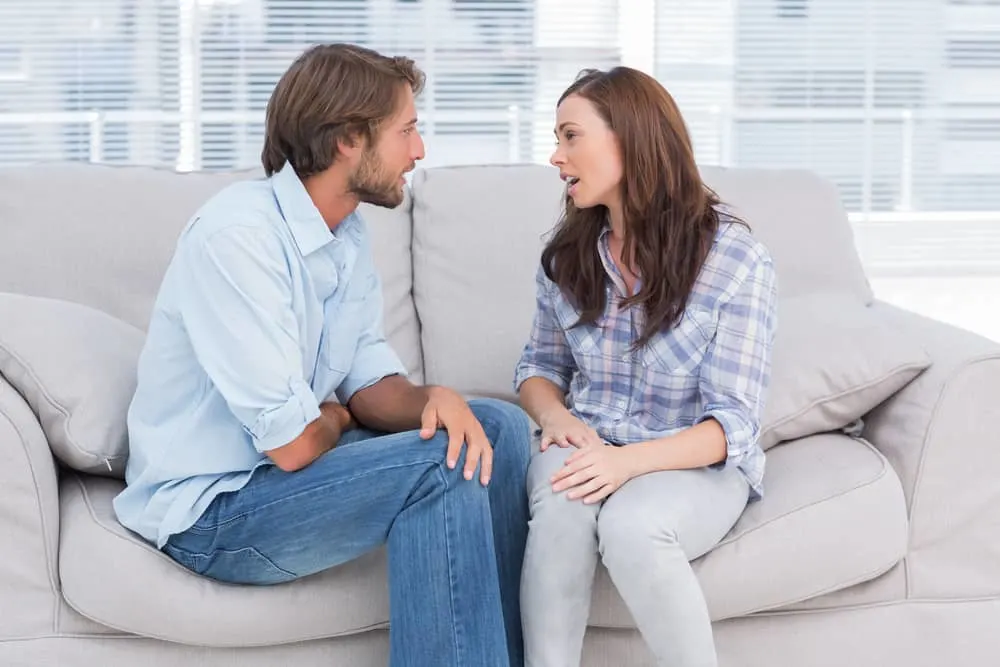 Ein junges trauriges Paar sitzt auf der Couch und redet