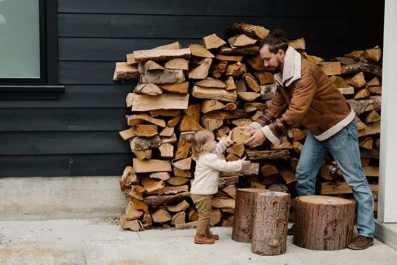 Ein kleines Mädchen hilft ihrem Vater beim Stapeln von Holz