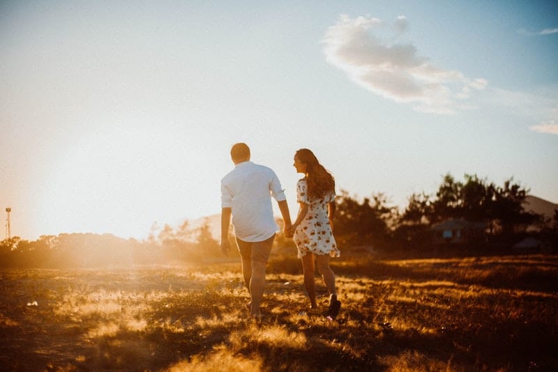 Ein liebendes Paar geht über ein Feld in der Sonne