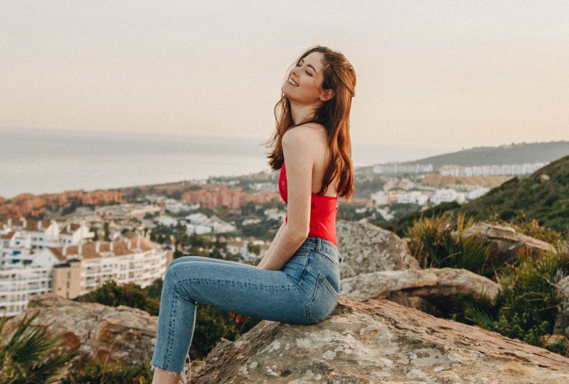 Ein schönes Mädchen sitzt auf einem Felsen auf einem Berggipfel