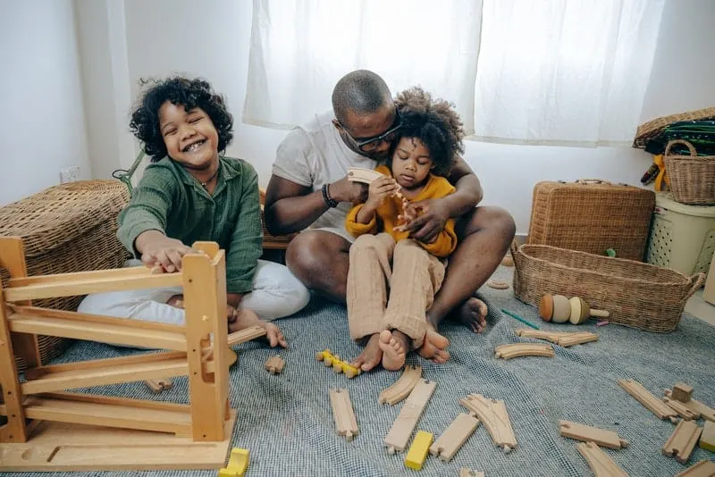 Ein schwarzer Mann mit seinen Töchtern sitzt auf dem Boden