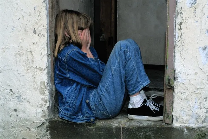 Ein trauriges kleines Mädchen sitzt am Fenster und weint