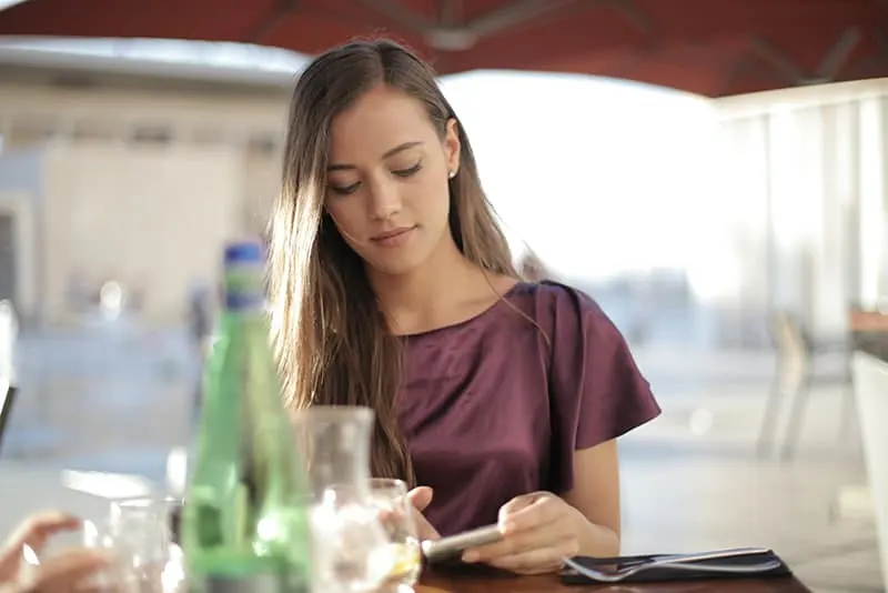 Eine Frau, die einen Anruf ablehnt, während sie alleine im Café sitzt