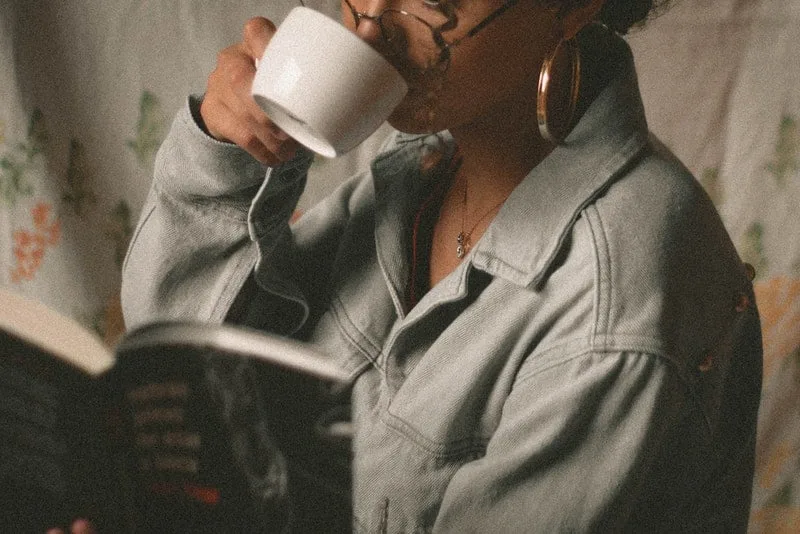 Eine Frau liest ein Buch und trinkt Tee