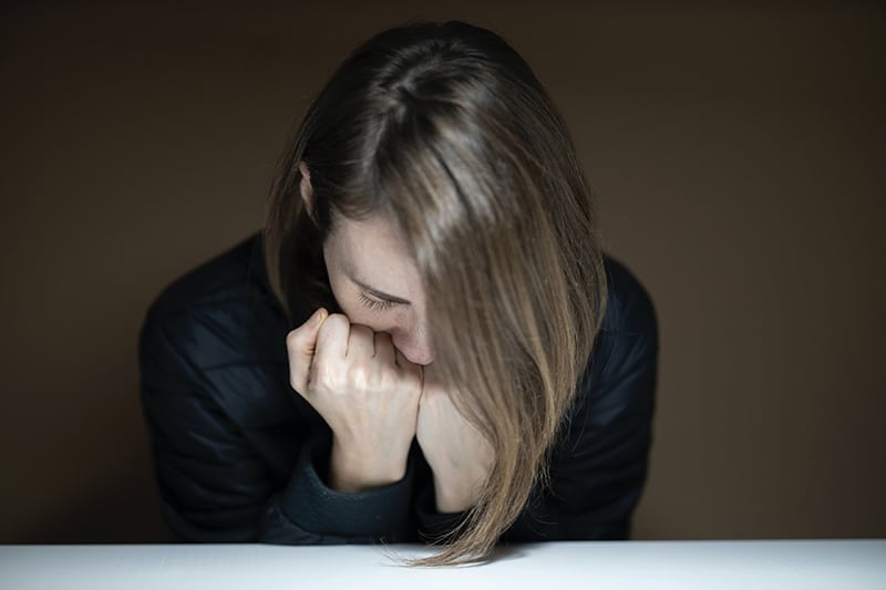 Eine verärgerte Frau stützte ihr Kinn auf die Handflächen am Tisch