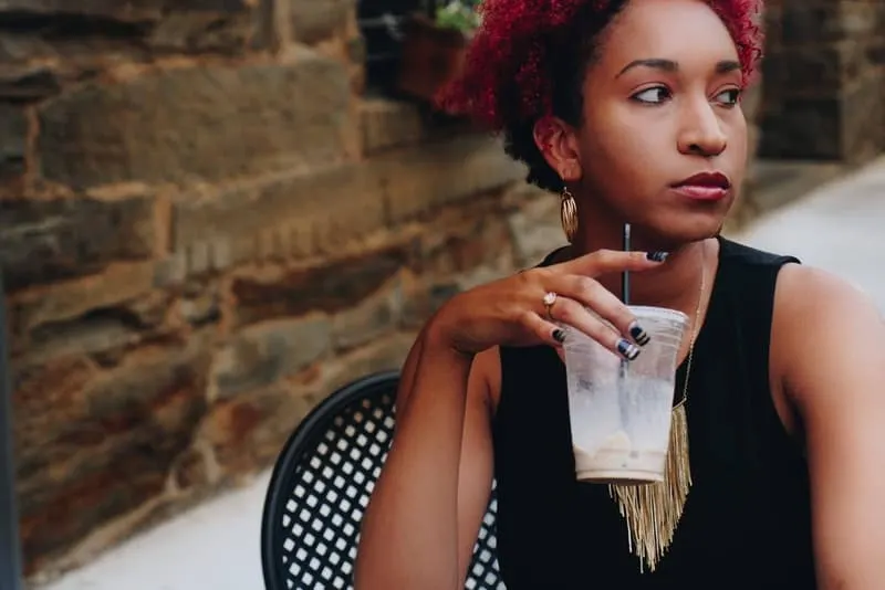 Eine wütende schwarze Frau sitzt und trinkt Frappe