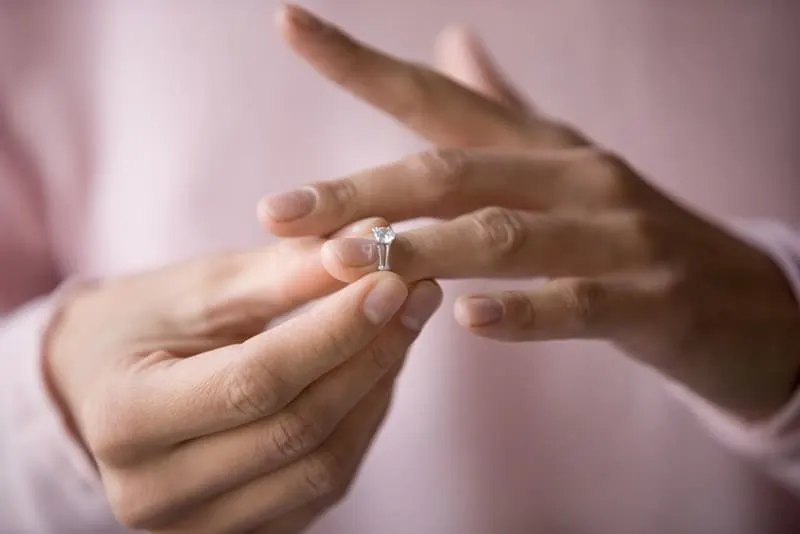 Frau, die Verlobungsring vom Finger nach Trennung abnimmt