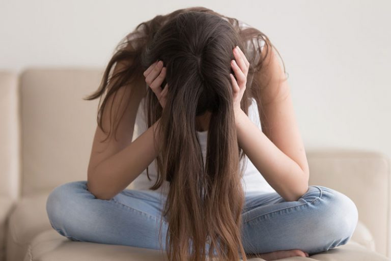 besorgte junge Frau sitzt auf der Couch