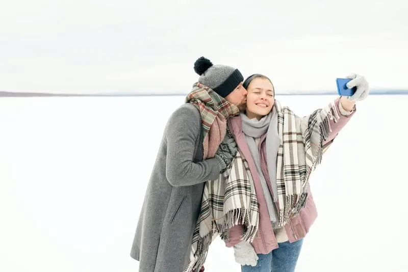 Liebespaar im Schnee, das ein Selfie-Foto macht