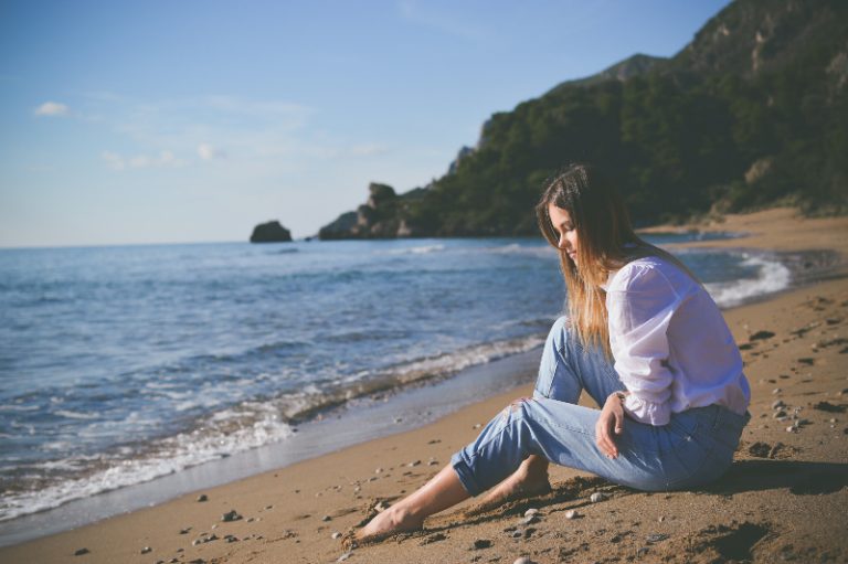 ein trauriges Mädchen, das am Meer sitzt