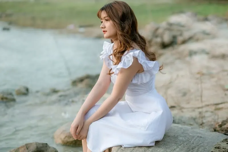 Ein trauriges Mädchen sitzt auf einem Felsen am Fluss