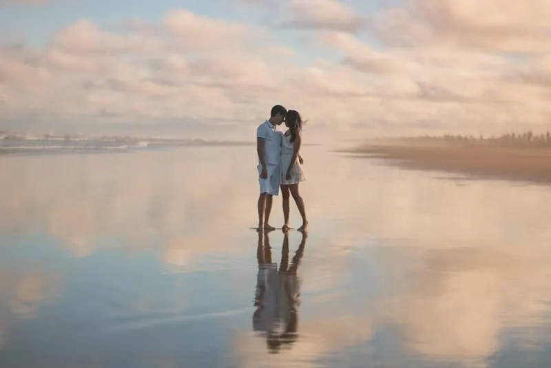 Eine Frau steht am Strand in den Armen eines Mannes