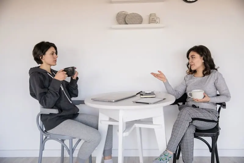 Zwei Frauen sitzen und reden und trinken Kaffee
