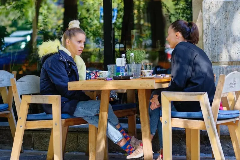 Zwei Freunde sitzen auf der Terrasse eines Cafés und unterhalten sich