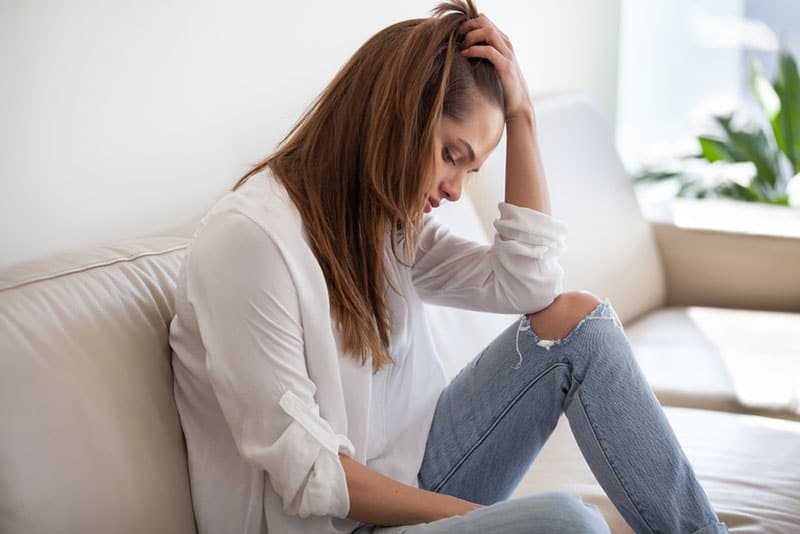 besorgte nachdenkliche Frau, die auf der Couch sitzt