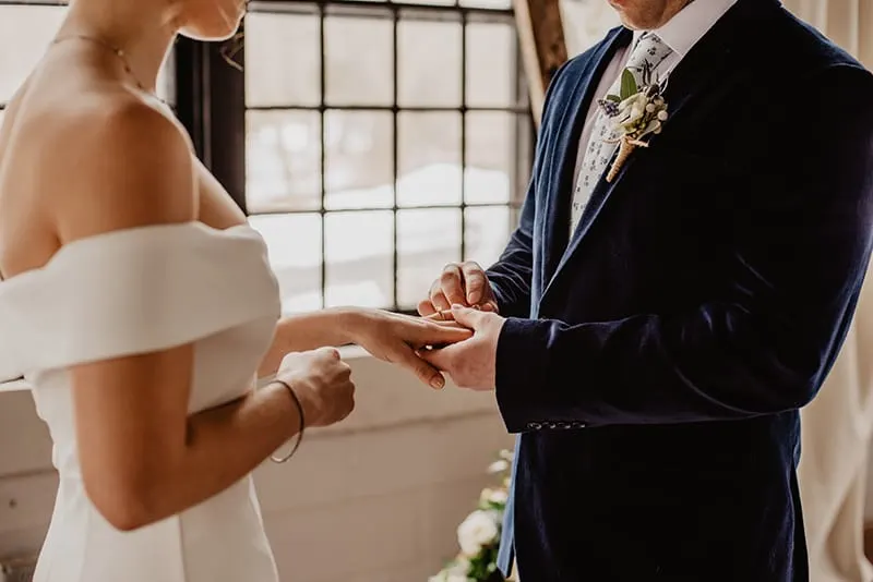 ein Bräutigam, der während der Hochzeitszeremonie einen Ring auf den Finger der Braut legt