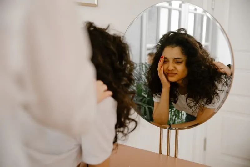 ein Mädchen weint vor einem Spiegel