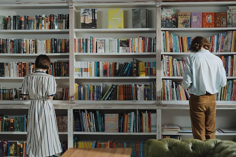 Ein Mann und eine Frau stehen in der Bibliothek nebeneinander