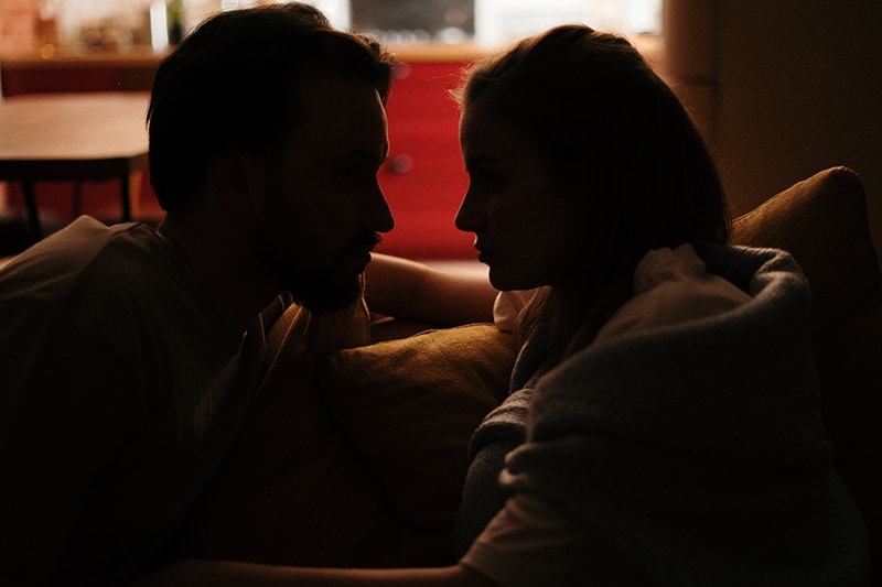 ein Paar, das sich abends auf dem Sofa gegenübersteht