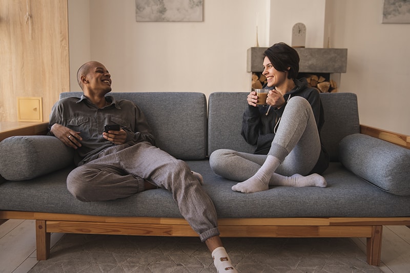 Ein fröhlicher Mann und eine Frau sitzen auf der Couch und reden