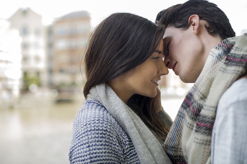 ein junges Paar, das sich gerade küssen will, während es in der Stadt steht