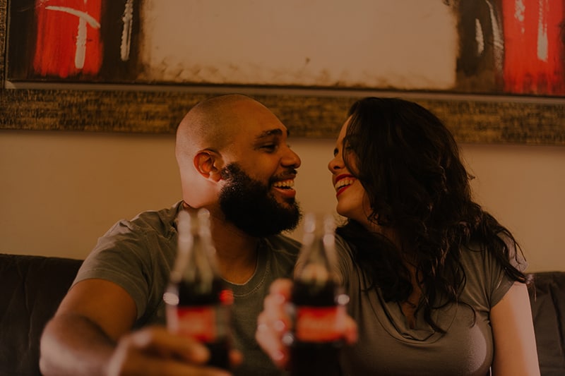Ein lächelnder Mann und eine Frau schauen sich an, während sie auf ein Date einen Toast mit Getränken trinken