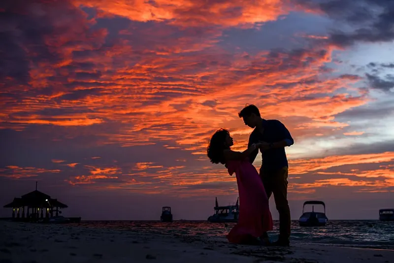 Ein Paar tanzt am Strand während des Sonnenuntergangs