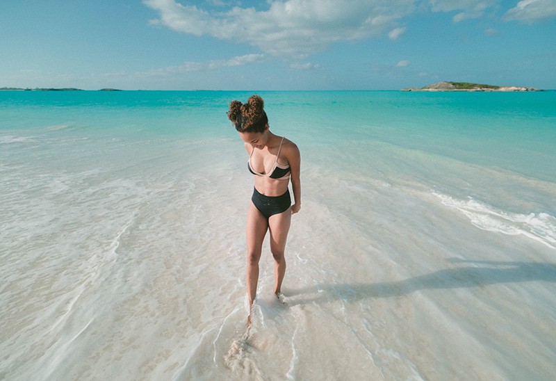 eine Frau, die am Strand steht und ins Wasser schaut