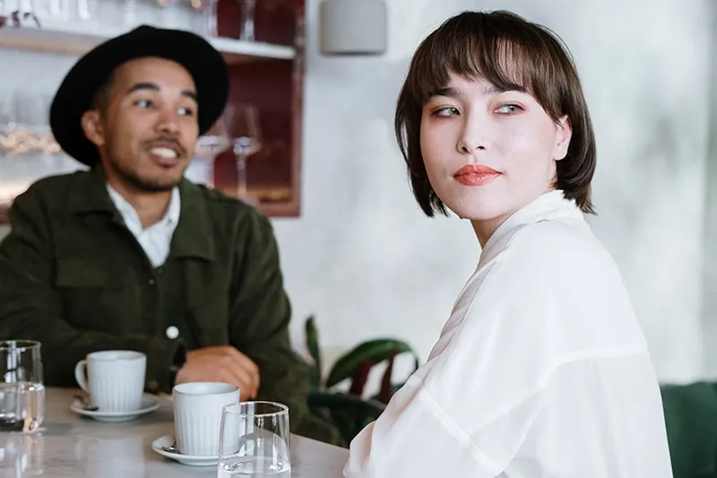 Eine Frau dreht den Kopf von einem Mann, der mit ihr spricht, während sie zusammen im Café sitzt