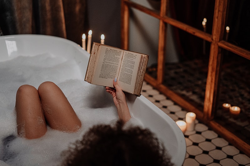 eine Frau, die ein Buch liest, während sie in der Badewanne liegt