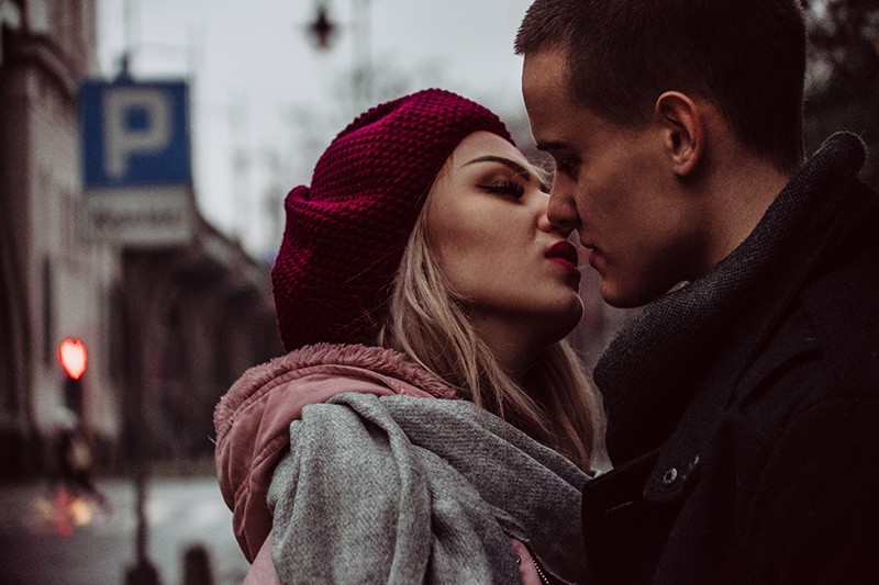 eine Frau, die gerade einen Mann küssen will, während sie zusammen auf der Straße steht