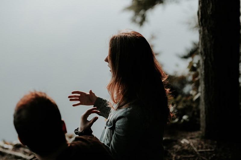 eine Frau, die sich mit einem männlichen Freund unterhält und mit den Händen gestikuliert