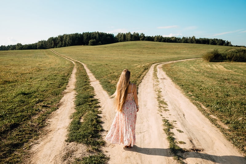 eine Frau, die vor zwei Straßen steht und entscheidet, welchen Weg sie gehen soll