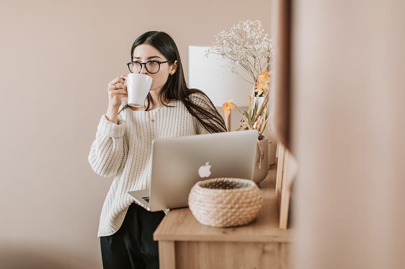 eine Frau, die einen Kaffee trinkt, während sie in der Wohnung steht