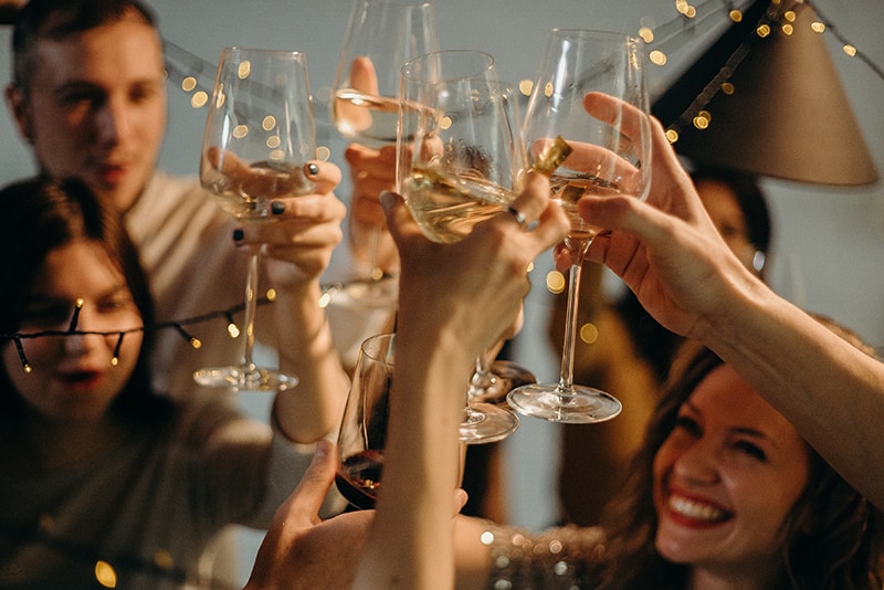 eine fröhliche Gruppe von Freunden, die einen Toast mit einem Glas Wein trinkenv