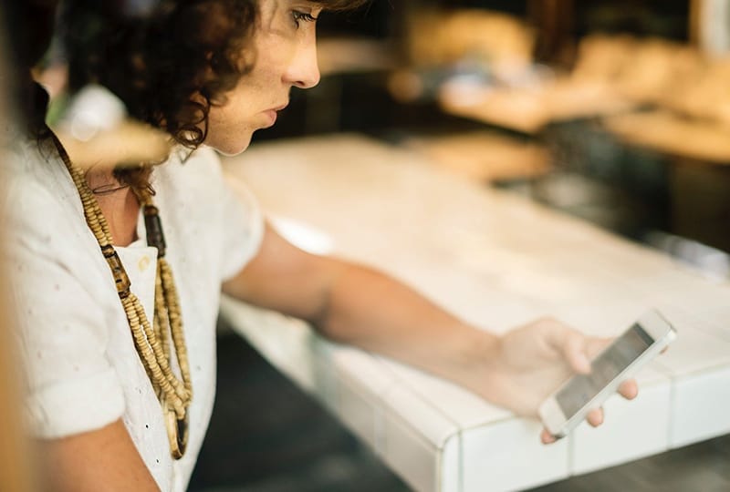 eine traurige Frau, die ihr Smartphone hält und auf einen Anruf wartet