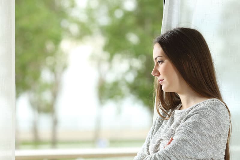 junge ernste Frau, die durch das Fenster schaut