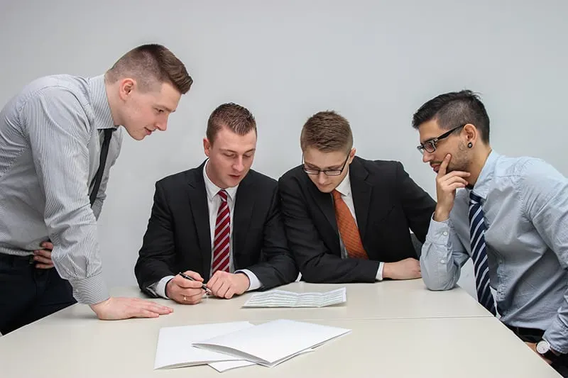 vier Kollegen schauen während des Meetings ein Papier auf den Tisch